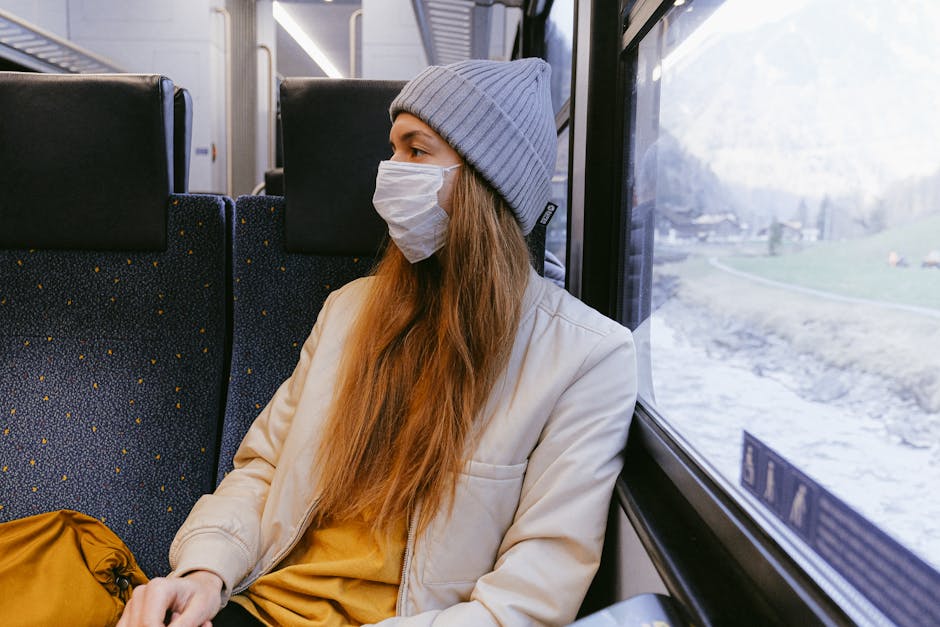 Woman on train wearing beanie and mask